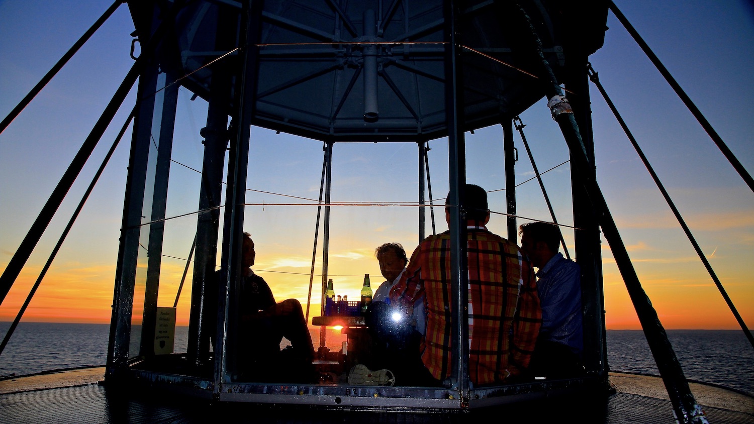 Gäster sitter uppe i lanterninen under solnedgången.
